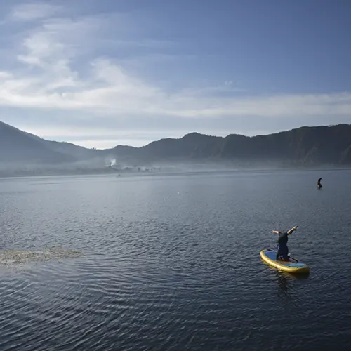 Student balancing on a paddleboard during 200-hour yoga teacher training retreat.