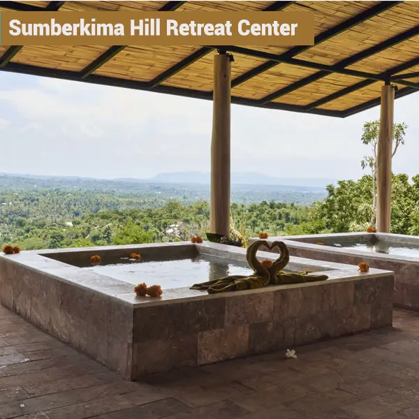 Outdoor stone spa bath decorated with marigolds at Sumberkima Hill retreat center with valley views in Northwest Bali