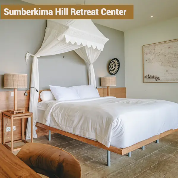Bright private room with white canopy bed and wooden furniture at Sumberkima Hill retreat center in Bali