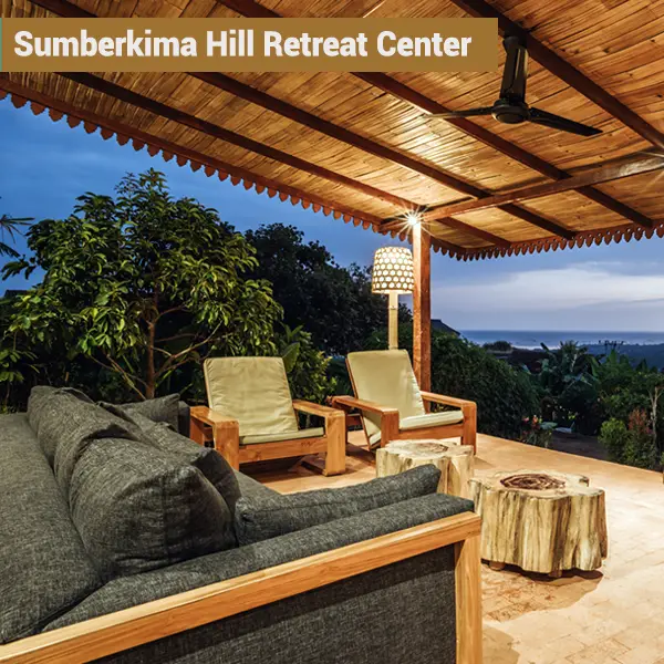 Open-air terrace lounge at night at Sumberkima Hill retreat center with ocean view in Northwest Bali