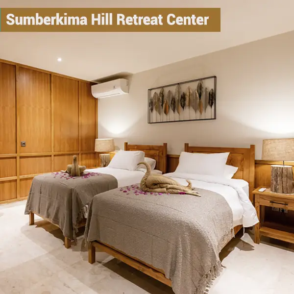 Shared twin room with wooden furniture and floral decoration at Sumberkima Hill retreat center in Bali